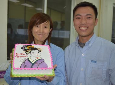現地社員から貰ったケーキを手に記念撮影をするS（左）